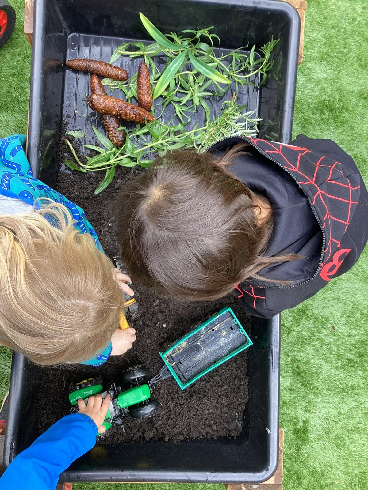 Children exploring a soil tray with natural materials at Wibli Wobli Cardiff nursery