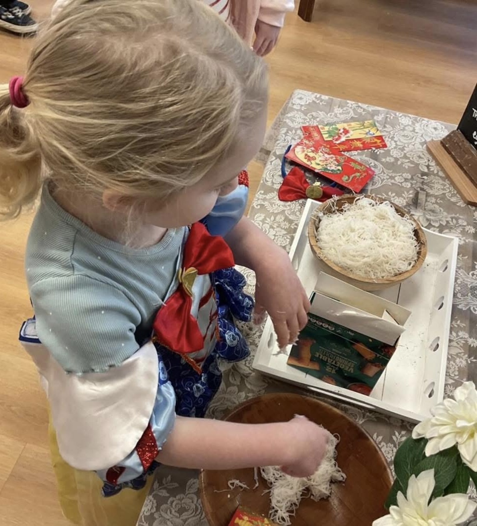 A child dressed as Snow White exploring a Chinese New Year sensory tray at Wibli Wobli Newport