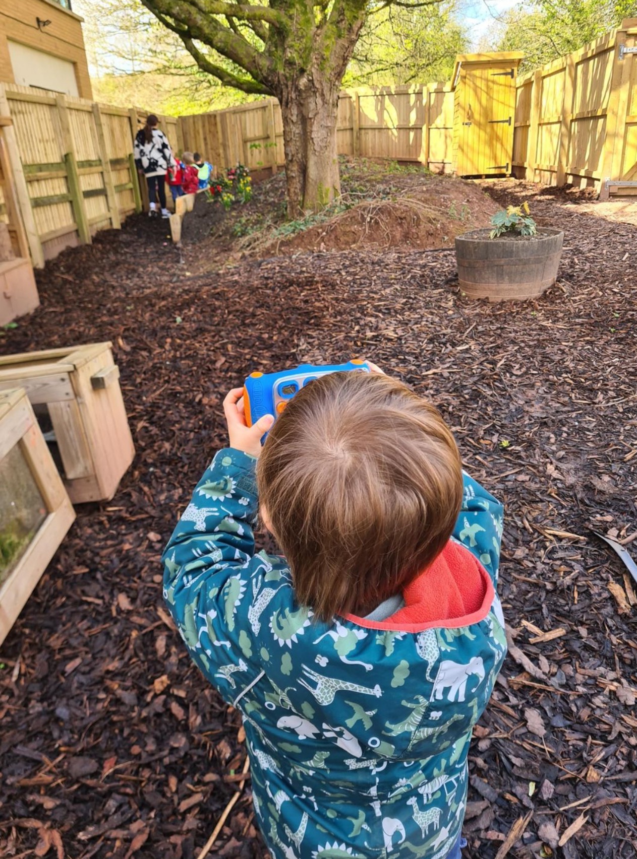 A child exploring the forest school woodland with a toy camera