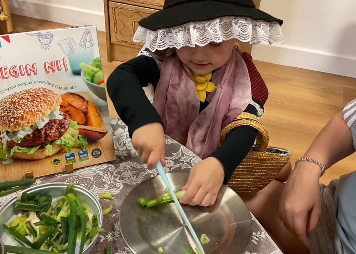 Child in traditional Welsh costume chopping vegetables during a Wibli Wobli activity