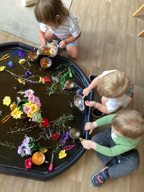 Children exploring a tray of natural flowers and materials at Wibli Wobli Cardiff nursery