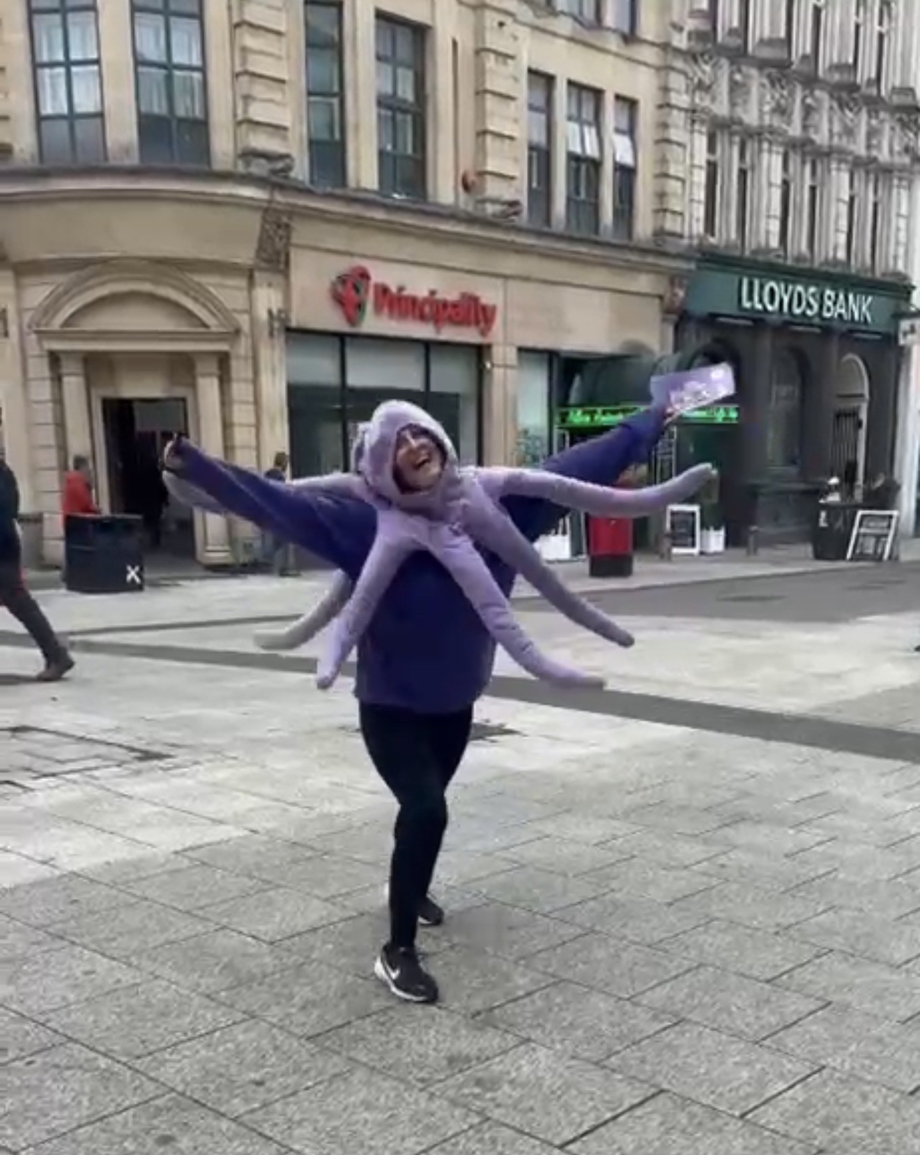 A nursery team member in a large purple octopus costume enjoying a community day in Cardiff city centre